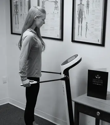 A woman is standing on the treadmill in her room.